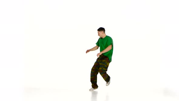 Talanted Young Dancer Man in Green Shirt Goes on Dancing Breakdance on White