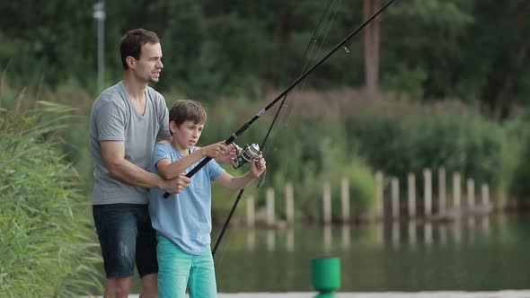 Teenage Boy Learning To Fish with Father's Help