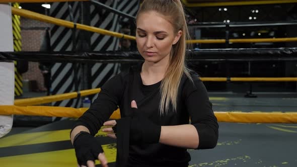Young Girl Bandaging Her Hands with a Black Bandage Before Boxing Training