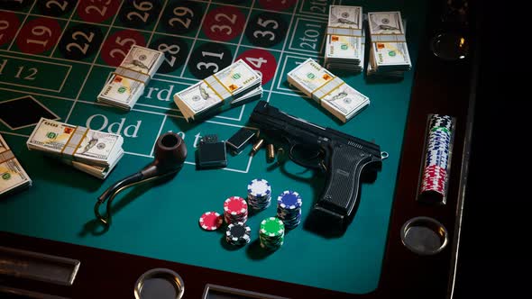 Guns with bullets, money and chips on a roulette table in a casino. Gambling.