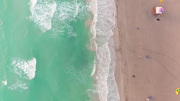 Vertical drone video over the waterline of a beach