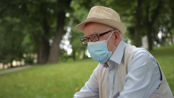 Old Man in a Medical Mask Sitting in the Park