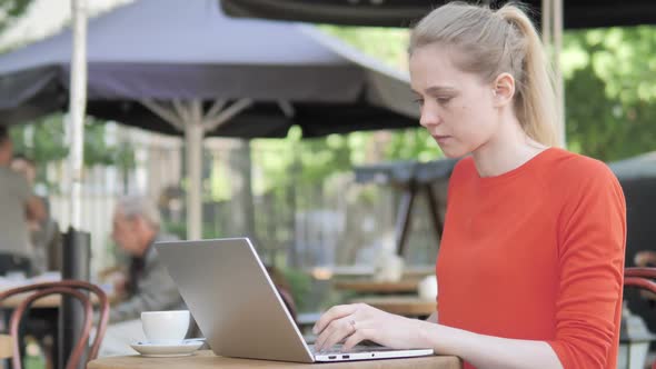 Young Woman Working on Laptop While Sitting in Cafe Terrace