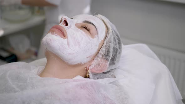 Girl Lies on the Table at the Doctor Beautician with White Cream