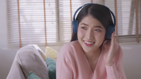 Asian woman uses her smartphone. uses headphones to listen to music