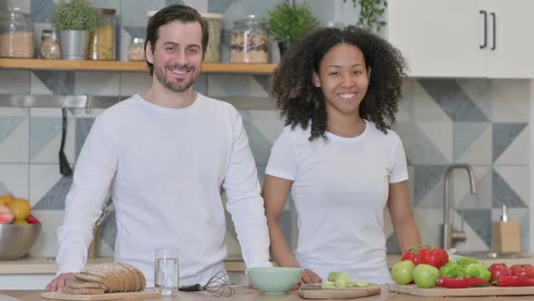 Mixed Race Couple Smiling at Camera in Kitchen