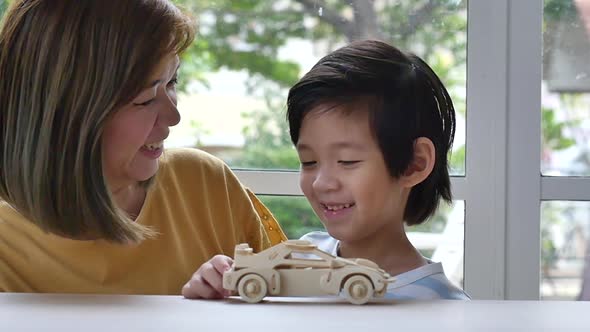 Asian Mother And Son Playing Wood Toy Car Together