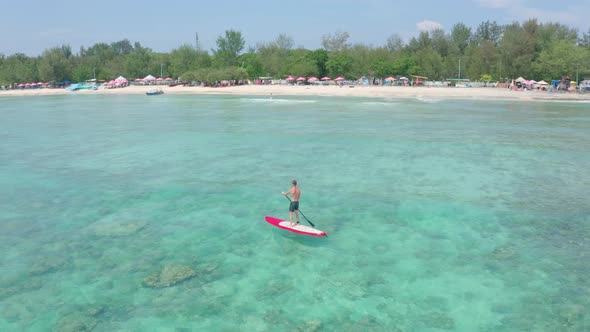 Aerial View of Young Male Surfer Floats on Calm Transparent Azure Waves