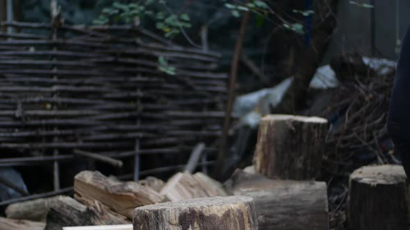 Man Chops Wood Outdoors in Slow Motion. Man's Hands Working with Ax. A Man Woodcutter Chops Tree