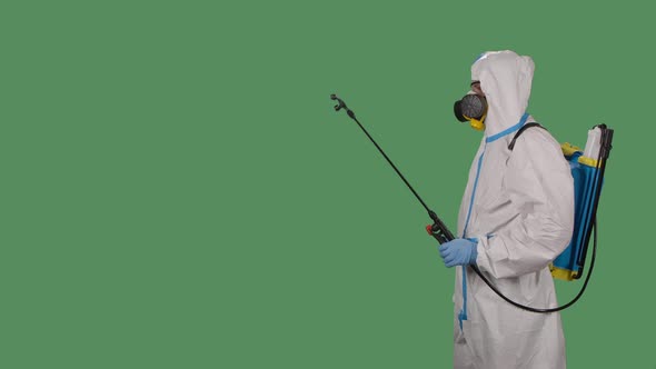 Side View Man in a Protective Suit with a Pressure Washer Disinfects Infected Area with Antiseptic