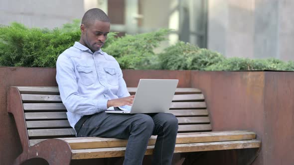 Focused Young African Man Using Laptop Outdoor 