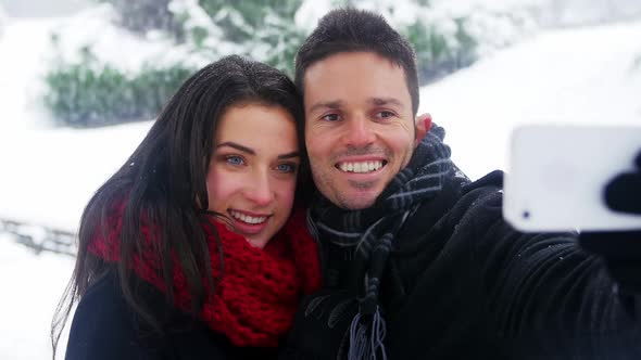 Couple taking selfie on mobile phone during winter