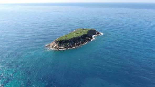 Small Green Island in Boundless Mediterranean Sea. White Gulls Flying Around Isle Over Blue Deep