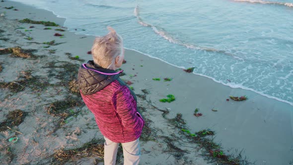 Grey Haired Lady Traveler Enjoys Waves View From Beach