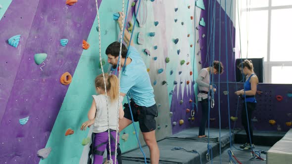 Male Instructor Talking To Little Girl in Climbing Gym Explaining Safety Requirements