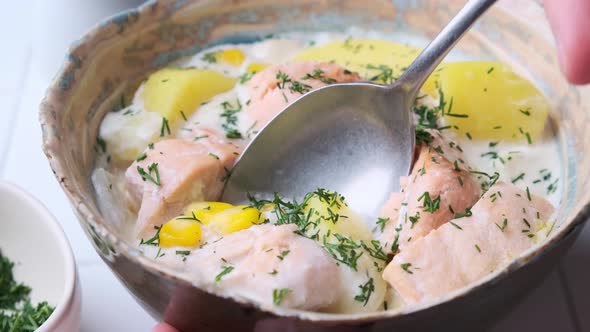 Norwegian fish soup with trout, potatoes and corn, gray background.