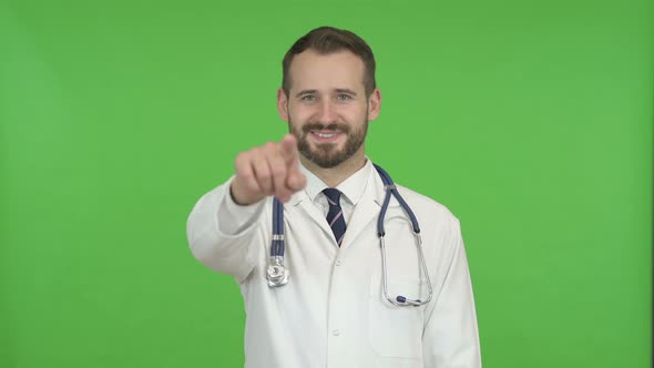 Cheerful Doctor Pointing Finger and Inviting Against Chroma Key