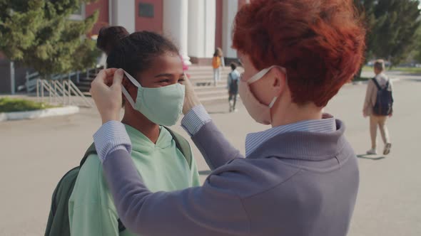 Caring Woman Putting Face Mask on Schoolgirl