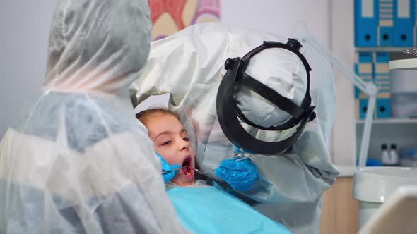 Close Up of Dentist in Coverall Examining Girl Patient in New Normal Dental Unit