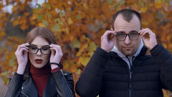 Portrait of a Young Couple Wearing Glasses Looking at the Camera Standing on the Street