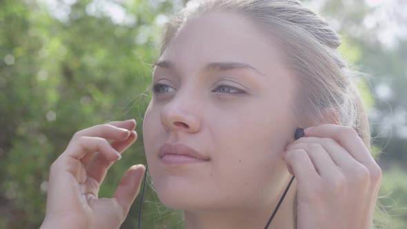 A young woman runner putting on earbuds before going on a run.