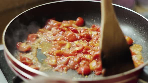 Stirring tomato sauce on pan while cooking