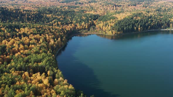 Aerial View of the Lake in the Autumn Colorful Forest Near the Hills and Mountains