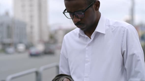 African Entrepreneur Scrolling on Smartphone while Waiting on Street