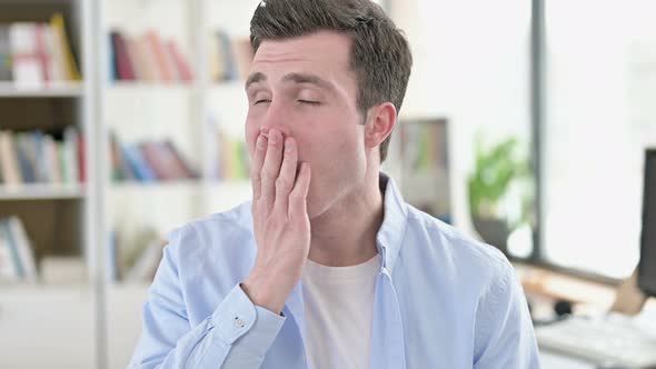 Tired Young Man Yawning in Office