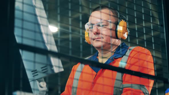 Industrial Operator in Protection Wear Filmed Through a Grid