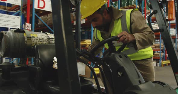 Male worker driving forklift in a warehouse