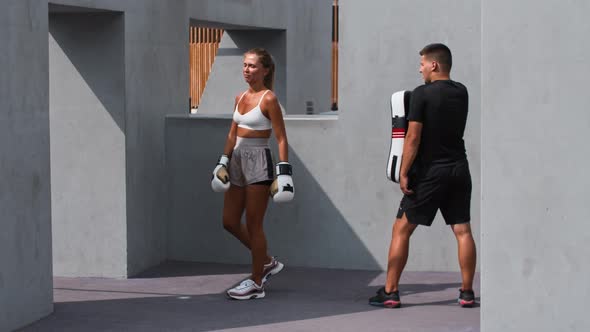 Young Woman in White Top Having a Boxing Training with Her Coach Outside  Kicking the Soft Protector