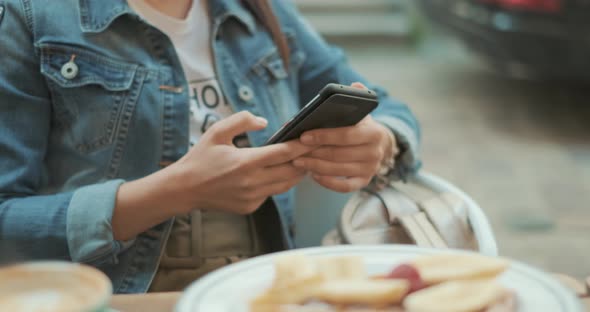 Hands of Young Woman Are Using Smartphone During Coffee Break in Cafe