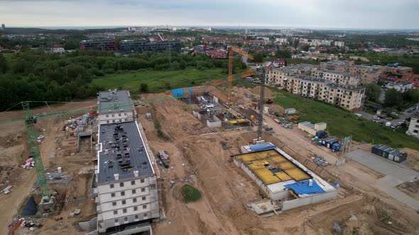 Aerial backwards shot of construction site with cranes in Gdansk City during cloudy day,Poland
