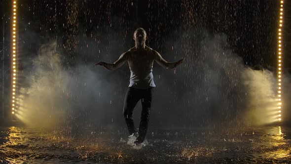 Male Dancer Dancing Elements of Salsa in the Pouring Rain. Silhouettes of a Man in Wet Clothes