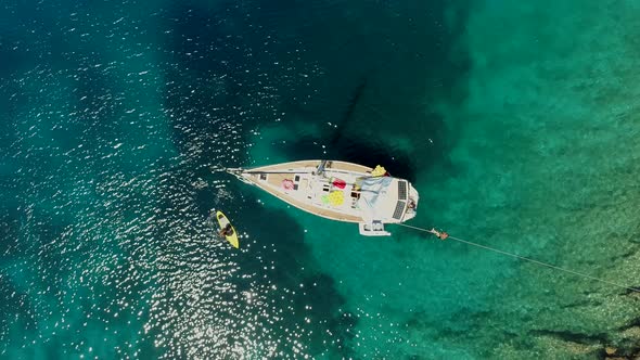Aerial view of paddle board next to boat anchored on the coast of Varko, Greece.