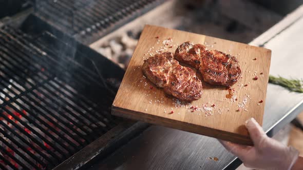 Chef Hands Putting Frying Meat on Wooden Board Serving Herbs