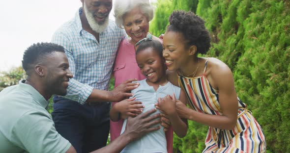 Portrait of happy african american family embracing and smiling in garden