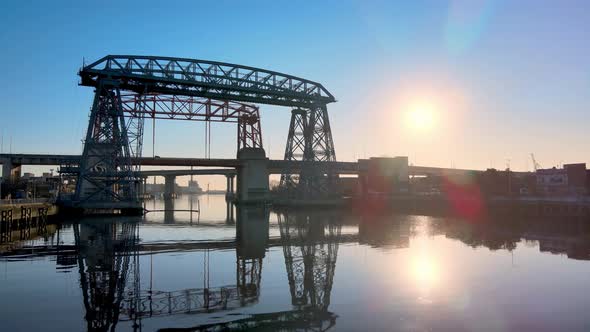 Low level aerial push in shot of ferry bridge Nicolas Avellaneda over the Matanza River during sunri