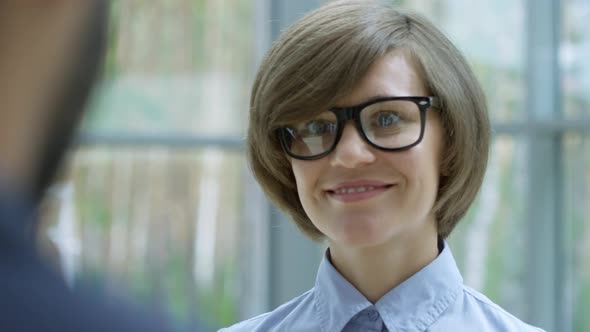 Pretty Businesswoman Smiling and Listening to Colleague