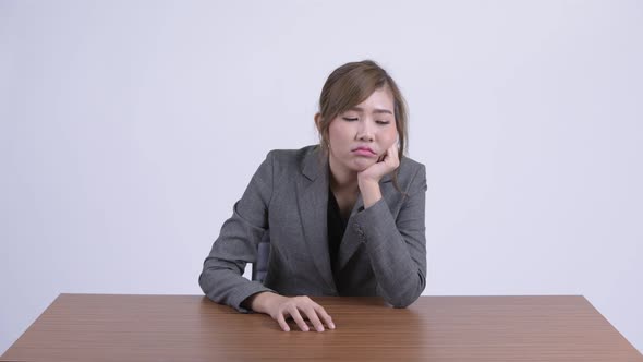 Young Stressed Asian Businesswoman Looking Bored at Desk