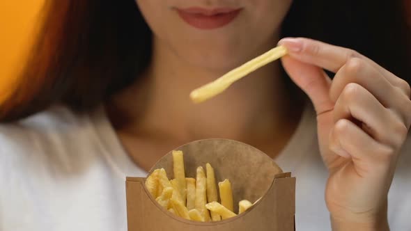 Beautiful Young Woman Eating Fatty French Fries, Unhealthy Fast Food, Close Up