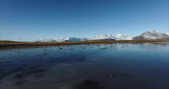 Marsh water and snowy hills with blue sky