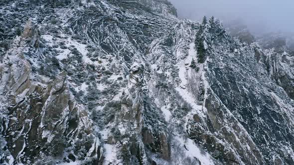 Panning aerial view of rugged cliffs covered in snow