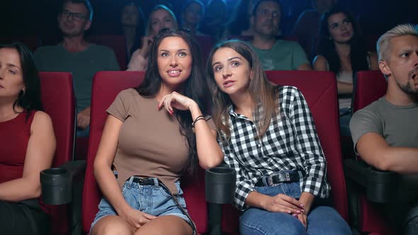 Two Female Friends Gossiping Discussing Scene Actors of Film Premiere Sitting on Armchair at Cinema