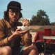 Young man eating from a bowl outdoors on camp site - VideoHive Item for Sale
