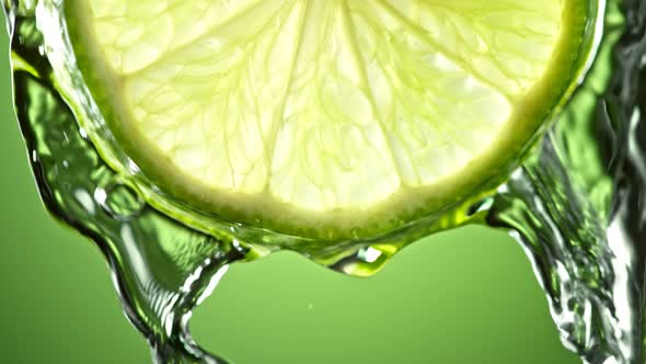 Super Slow Motion Macro Shot of Flowing Water From Lime Slice on Green Background at 1000Fps