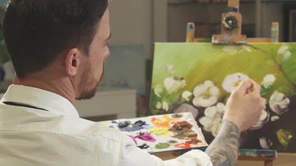 Rear View Shot of a Male Artist Working on a Painting at His Art Studio