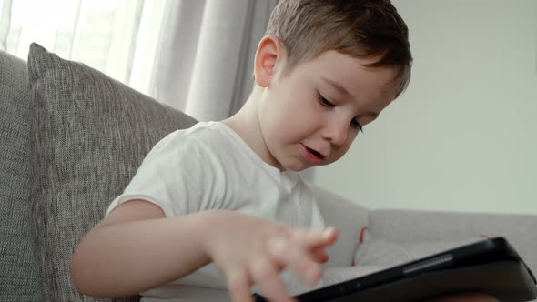 Curious Cute Preschool Kid Boy Using Digital Tablet Technology Device Lying on Carpet Floor Alone