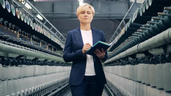 A Woman in a Business Suit is Supervising Sewing Equipment